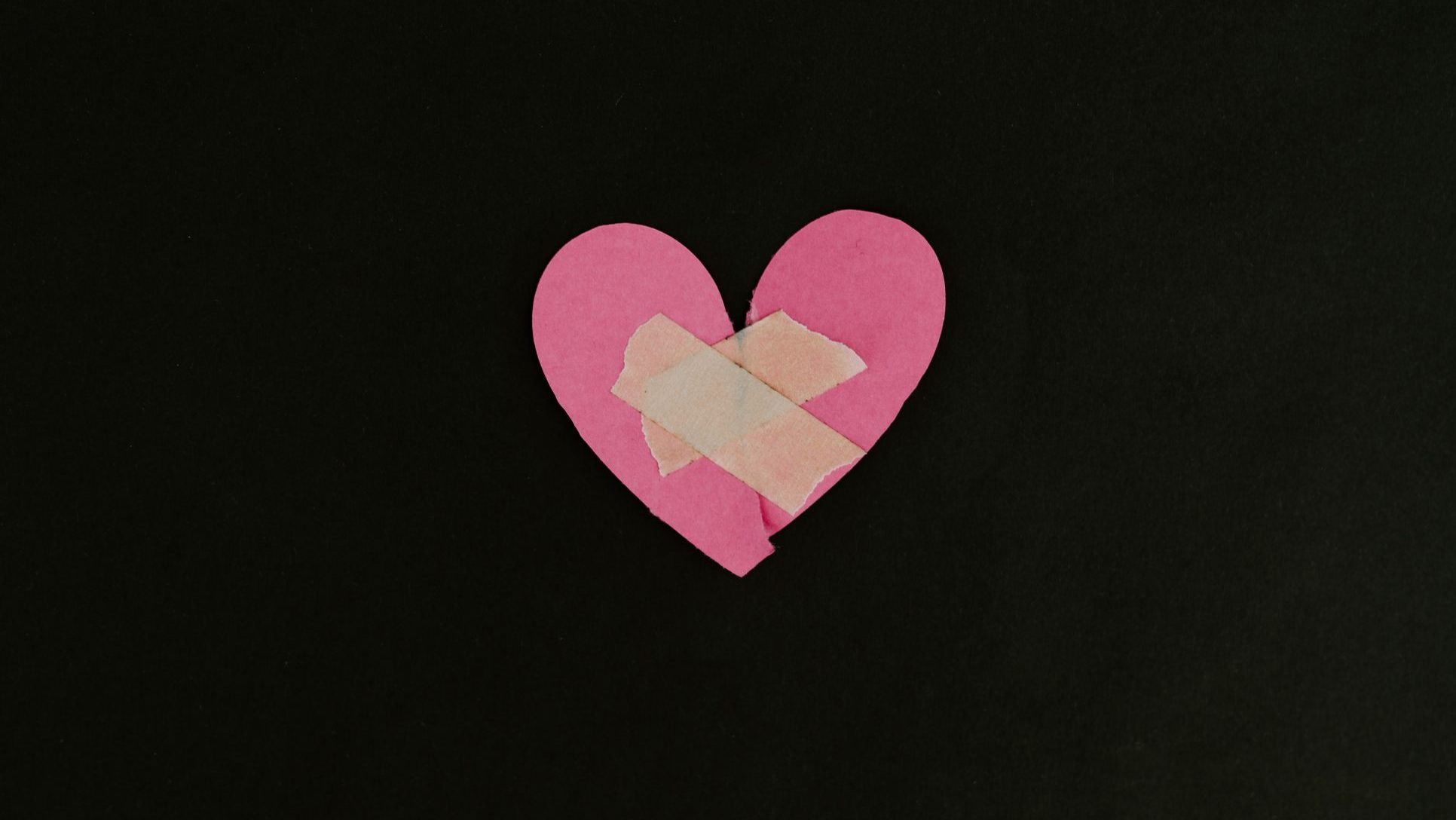 Corazón osa con una tirita puesta en el centro sobre fondo negro